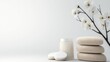 © wira - A serene spa scene featuring a jar of cream, cotton pads, stacked stones, and delicate white cherry blossoms against a minimalist backdrop.