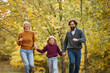 © Stockphotodirectors - A family is having fun as they walk hand in hand through a park. The vibrant autumn foliage creates a cheerful backdrop for their joyful weekend outing.