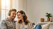 © INSPIRIA.K - Young couple smiling while listening to music on headphones on couch in living room