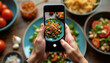 © Pete - Person takes photo of salad with smartphone. Hands holding phone, focus on food. Fresh healthy meal, tomatoes, greens. Food photography, mobile device, social media concept.