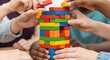 © Sahnaj - A group of diverse hands carefully building a tall tower with colorful wooden blocks, symbolizing teamwork, strategy, and fun