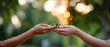 © perfectlab - Two hands exchanging a stack of coins outdoors with blurred green and golden bokeh background symbolizing financial transaction and trust