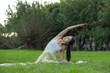 © leungchopan - Woman performing outdoor stretching routine in green park