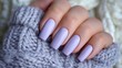 © buraratn - Elegant lavender nail polish on manicured fingers resting on a cozy knitted sweater showcasing a stylish and relaxing aesthetic for beauty enthusiasts