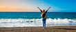 © M.studio - happy woman in casual attire with arms up of joy on beautiful beach at sunset