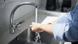 © Varos - Close-up of a person's hands being washed under a stream of clean water from a modern faucet to prevent germs and maintain hygiene