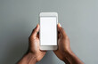 © Pete - Dark skin man holds white smartphone. Phone screen is blank and empty. Person touch cell mobile gadget. Modern tech communication device mockup at dark hand. App promo template