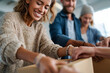 © Olha Havelia - close-up friends volunteering together packing donation boxes, supportive teamwork, warm connection,