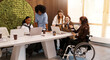 © Valerii Apetroaiei - Inclusive diverse business team working together, woman in wheelchair at office meeting