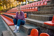 © Drazen - Mature athletic woman listening music over earbuds while relaxing on staircase during outdoor workout.