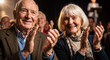 © Running opossum - elderly couple clapping at a joyful event with audience in background under warm lighting