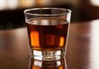 © twilight mist - Shot glass filled with amber spirit rests upon a polished wooden surface.
