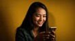 © CrazyJuke - Texting with a Smile: A young woman is captivated by the contents on her phone, illuminated against a bright background, her genuine smile hinting at the joy of her digital experience.