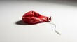 © Dara - A deflated red balloon on a white surface.
