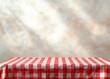 © tiger - Empty table with red and white checkered tablecloth against warm textured wall, cozy and inviting