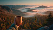 © Nischaa - Hand holding a wooden cup with a warm drink overlooking a serene misty mountain landscape at sunrise.
