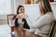 © qunica.com - A cheerful indoor scene showing two women talking and sharing a moment with drinks, highlighting friendship and enjoyment in a relaxed atmosphere.