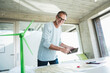 © Westend61 - Happy man touching tablet PC screen and standing near wind turbine model at desk