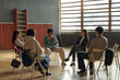 © TrueFrame Collective - Group of multiethnic teenagers and young adult Caucasian woman sitting in circle discussing psychology topics in classroom setting, students engaging in group therapy or counseling session