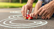© GrapikHill - Parent and child s hands guiding a small red toy car along a chalk drawn race track on pavement