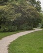 © Ulrich - Winding gravel path through lush green park in summer