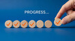 © HADI INCREDIBLE - Hand placing wooden circle with a checkmark on a line of other circles, signifying progress.