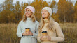 © rohappy - Modern happy women friends talking with coffee together in the park, smiling girlfriends outdoors