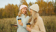 © rohappy - Modern happy women friends talking with coffee together in the park, smiling girlfriends outdoors