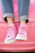 © Margarita Ratatosk - Caucasian woman feet in pink sneakers with jeans sitting on a classic pink car. Happy and playful feeling for fashion and lifestyle concept.