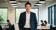© yevhen89 - Confident Asian businessman stands smiling with hands in pockets in a bright open modern office space