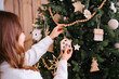 © reddish - Hands decorating a natural Christmas tree with wooden ornaments and soft lights