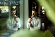© BGStock72 - Man engaged in a conversation while standing by a large window in a modern office