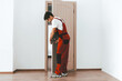 © Prostock-studio - A skilled worker in red overalls is focused on installing a door in a clean, modern space. The room features light-colored walls and a wooden floor, creating a fresh atmosphere.