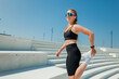 © muse studio - Woman in athletic wear stretches on steps before exercise