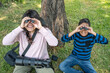 © JCarlos VBrito - Mother and son relaxing by a tree, smiling while observing nature with binoculars