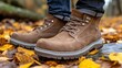 © imagineRbc - A person is wearing brown boots and standing on a pile of leaves. The boots are made of leather and have a brown color. The person is wearing jeans and has a casual and relaxed look