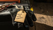 © MP-AI - Work glove with help wanted tag on wooden surface. Conceptual message illustrates labor market shortages and urgent need for hiring and recruitment for an extra hand