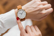 © Paintbrush - A person checking the time on a wristwatch with a white sleeve visible.