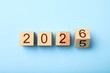 © New Africa - New year. Flipping cube with number 5 and 6 to make 2026 on light blue background, top view