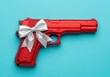 © Laki - A red toy gun with a silver bow on a blue background is a metaphor for the gift of violence