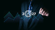 © PRIM - Businessman pointing at digital target icon with 2027 and rising line graph, symbolizing future strategy, financial growth, data analytics, corporate planning, and market performance trends.