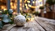 © P.G - Elegant white ornament with intricate design resting on rustic wooden table surrounded by soft glowing lights and green leaves, creating a cozy festive atmosphere
