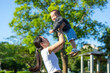 © leungchopan - Mother lifting baby joyfully in the air outdoors