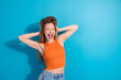 © deagreez - Young woman in orange crop top poses joyfully against blue background for lifestyle fashion shoot highlighting happiness and casual style