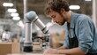 © CYBERPINK - A young man working in a factory. he is wearing a denim shirt and a black apron. he has curly hair and is focused on his work.