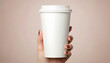 © Creative - PNG  - Closeup of a womans hand holding a disposable coffee cup against a beige background