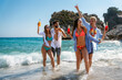 © NDABCREATIVITY - Happy friends partying at the beach with cold drinks. Carefree summer celebration by the sea