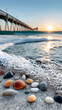 © KM - Seashells and pebbles on sandy beach with gentle waves and pier in background during beautiful sunrise in North Carolina. scene evokes tranquility and natural beauty