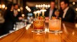 © Anggree - Elegant Cocktails on Bar Counter in Upscale Nightclub with Blurred Group of Men Socializing