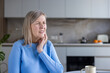 © Liubomir - Mature woman feeling intense pain in her jaw or neck, touching her cheek and clenching her teeth, indicating discomfort and need for relief or medical attention